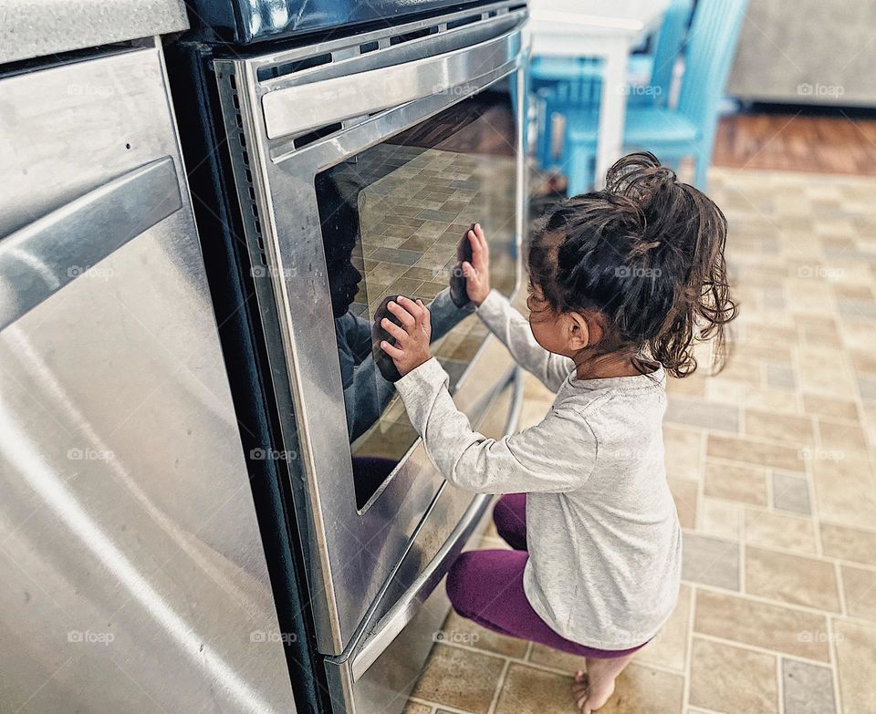 Little girl waits on dinner, watching food cook in the oven, toddler girl watches Thanksgiving meal cook in the oven, toddler girl helps mommy in the kitchen, toddlers cooking 