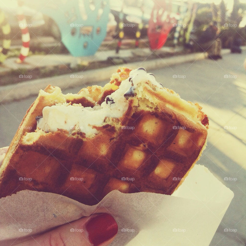 A hand holding an ice cream waffle sandwich.