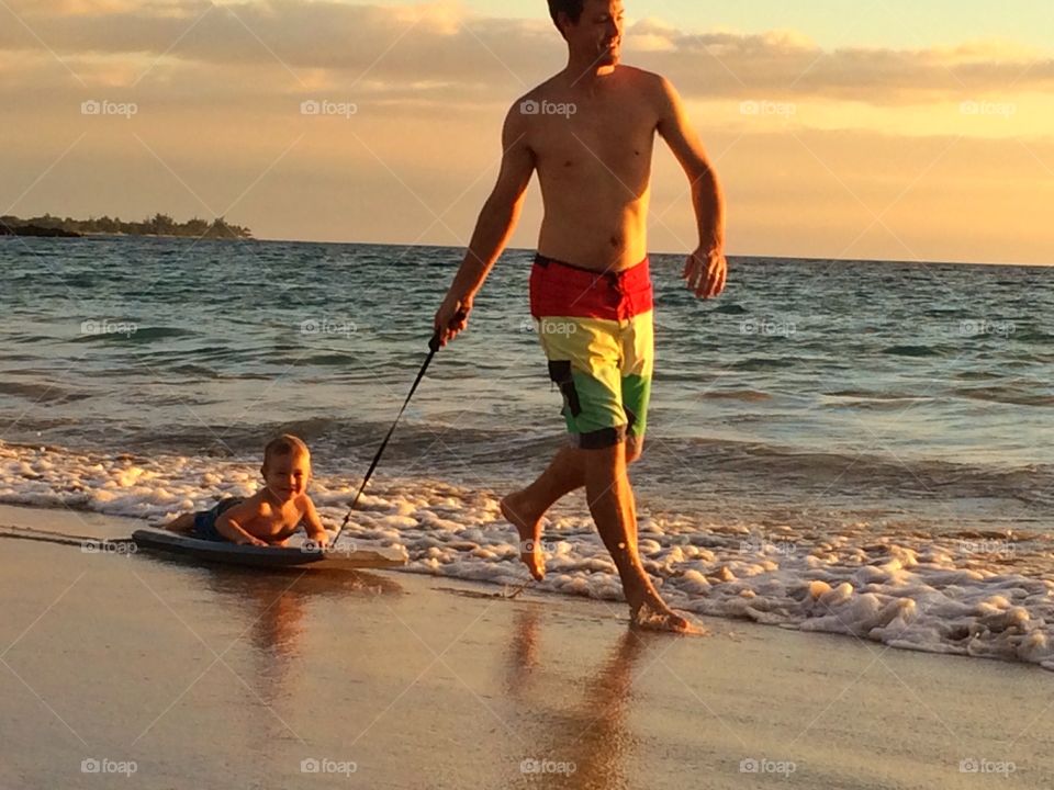 Boogie board training . Dad pulling his son on a boogie board in Hawaii 