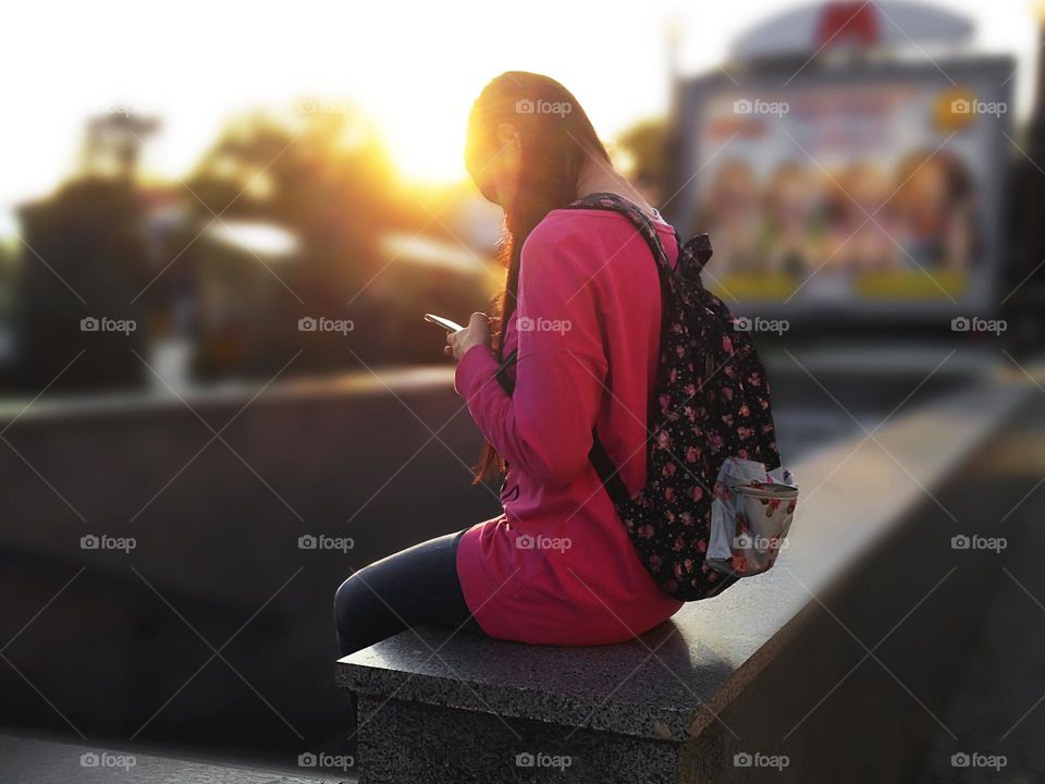 Student with mobile phone at sunset 