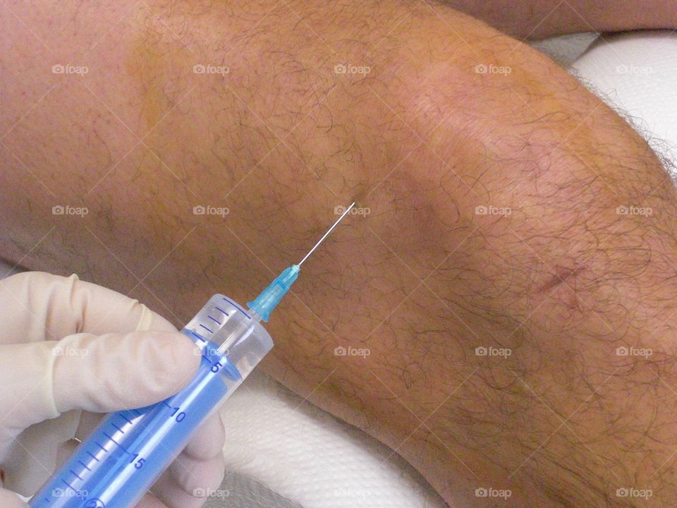 Health care worker injecting the knee joint