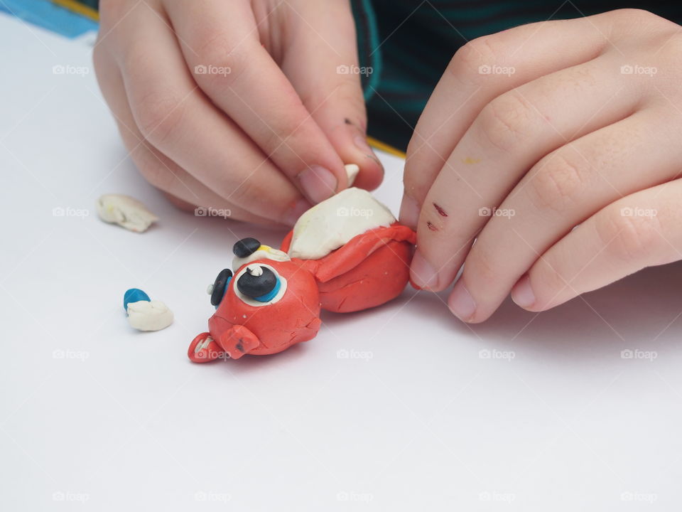 The child sculpts from plasticine a small figure of an animal.  Home creativity.