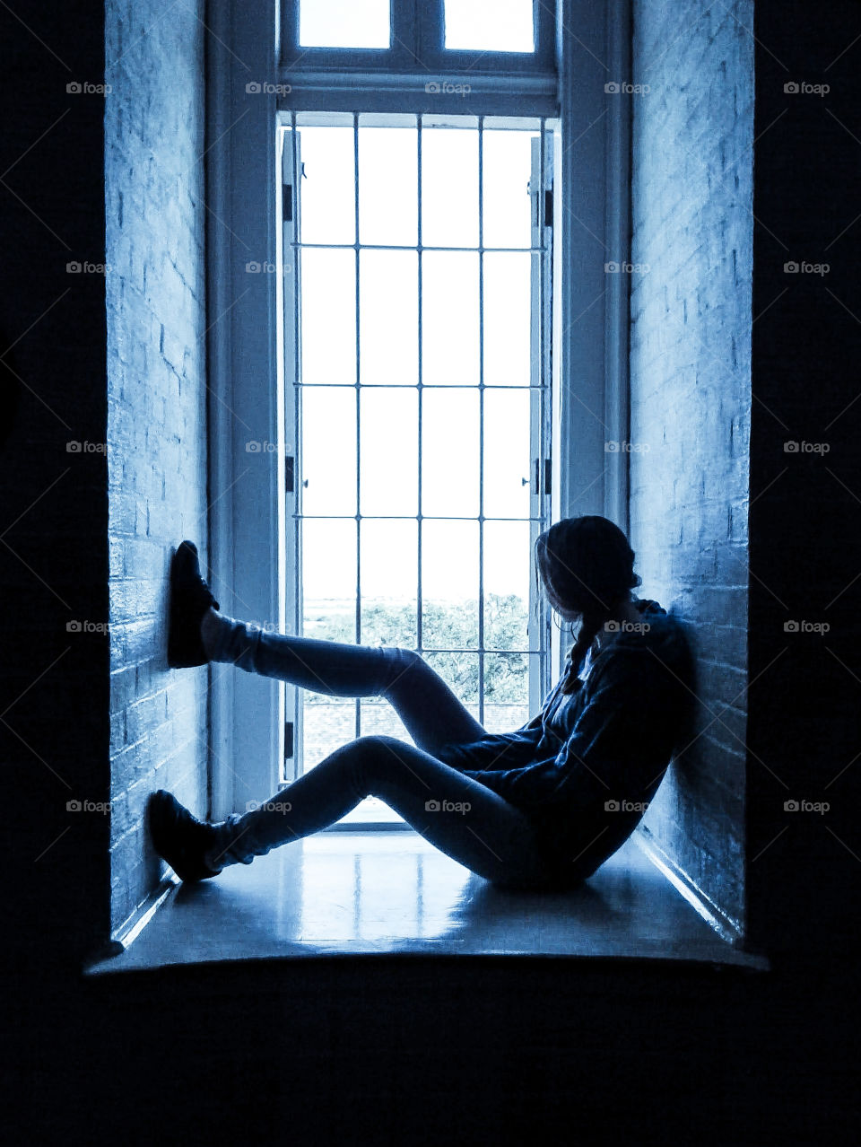 Girl sitting in a window well.