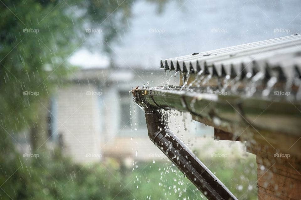 A heavy rain pours from the roof along the drainpipe