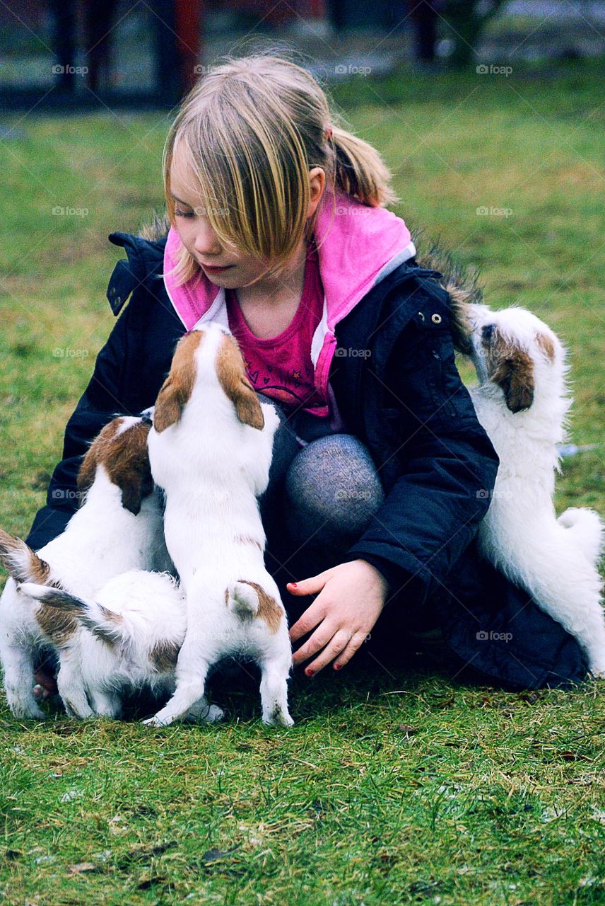 Girl playing with puppies on grassy field