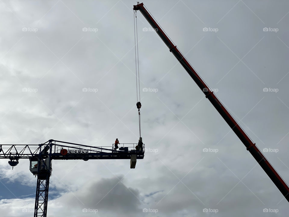 Silhouette of man working on construction cranes