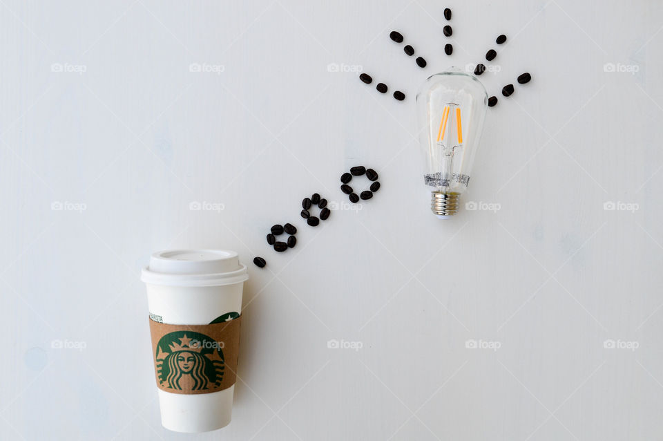 Starbucks coffee cup laid out on a white table with coffee beans appearing to sprout out of the top as a thought bubble with a lightbulb