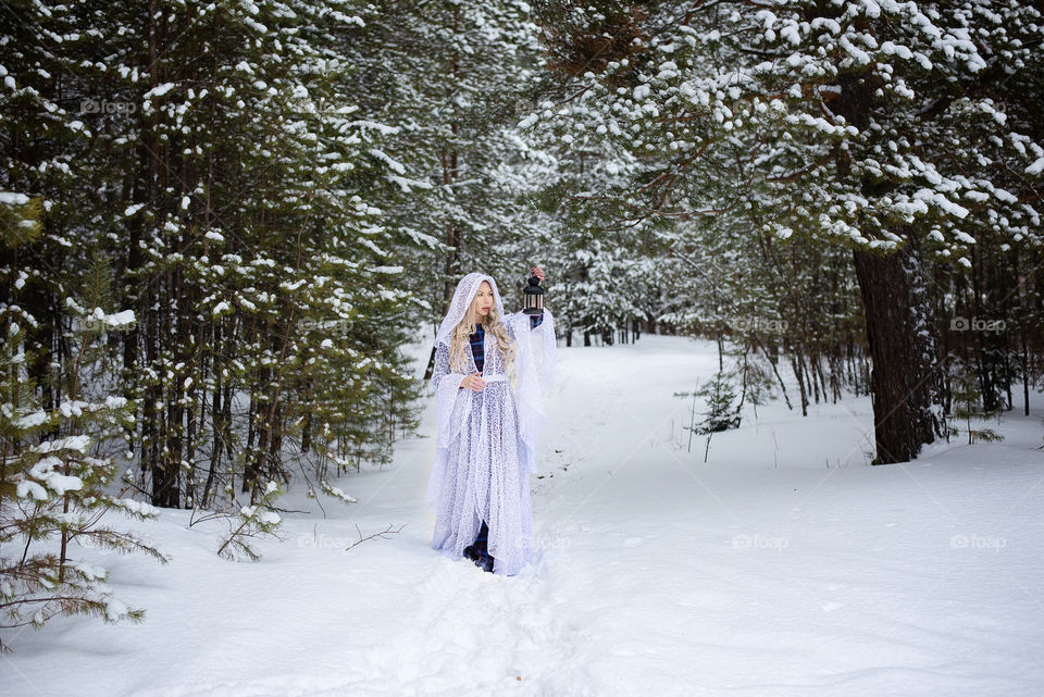 Woman standing on snow holding lantern in hand