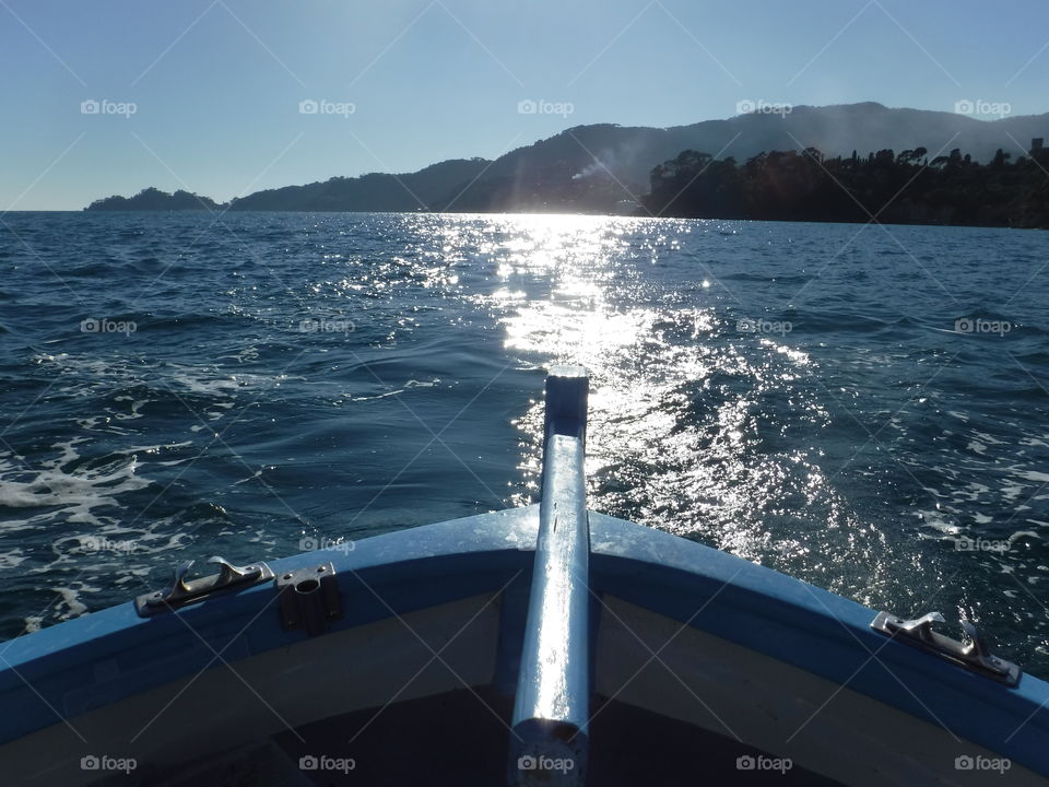 Barca   sole   mare. Barca in navigazione sulla scia del sole...... sullo sfondo la magnifica punta di Portofino (ge)

