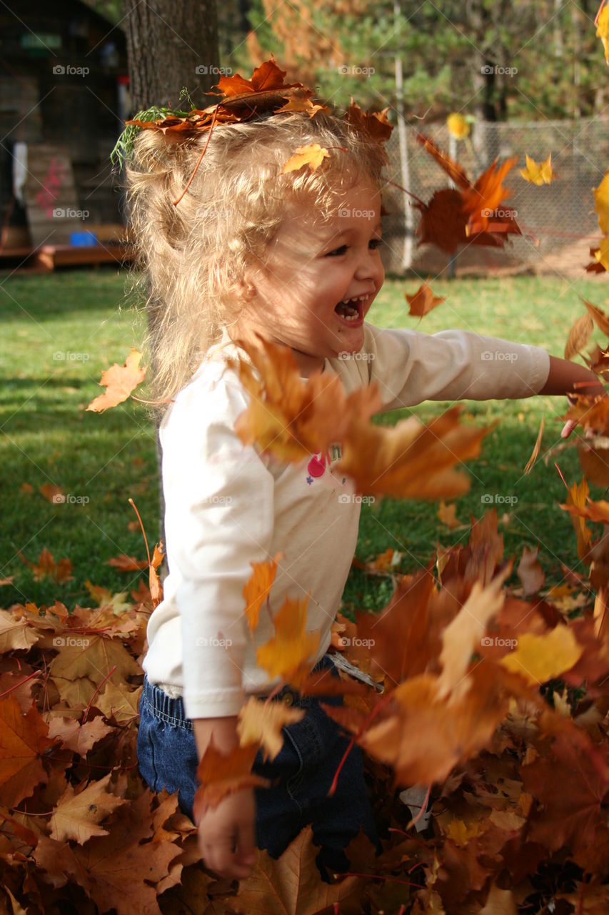 Toddler plays in fall leaves.