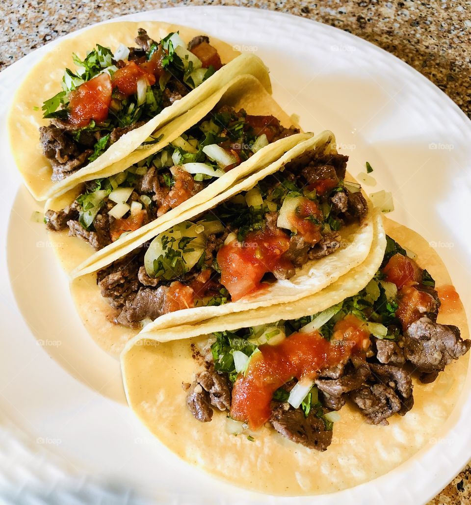 Four delicious Mexican tacos called "tacos de carne asada." They are very delicious and has lots of flavor. 