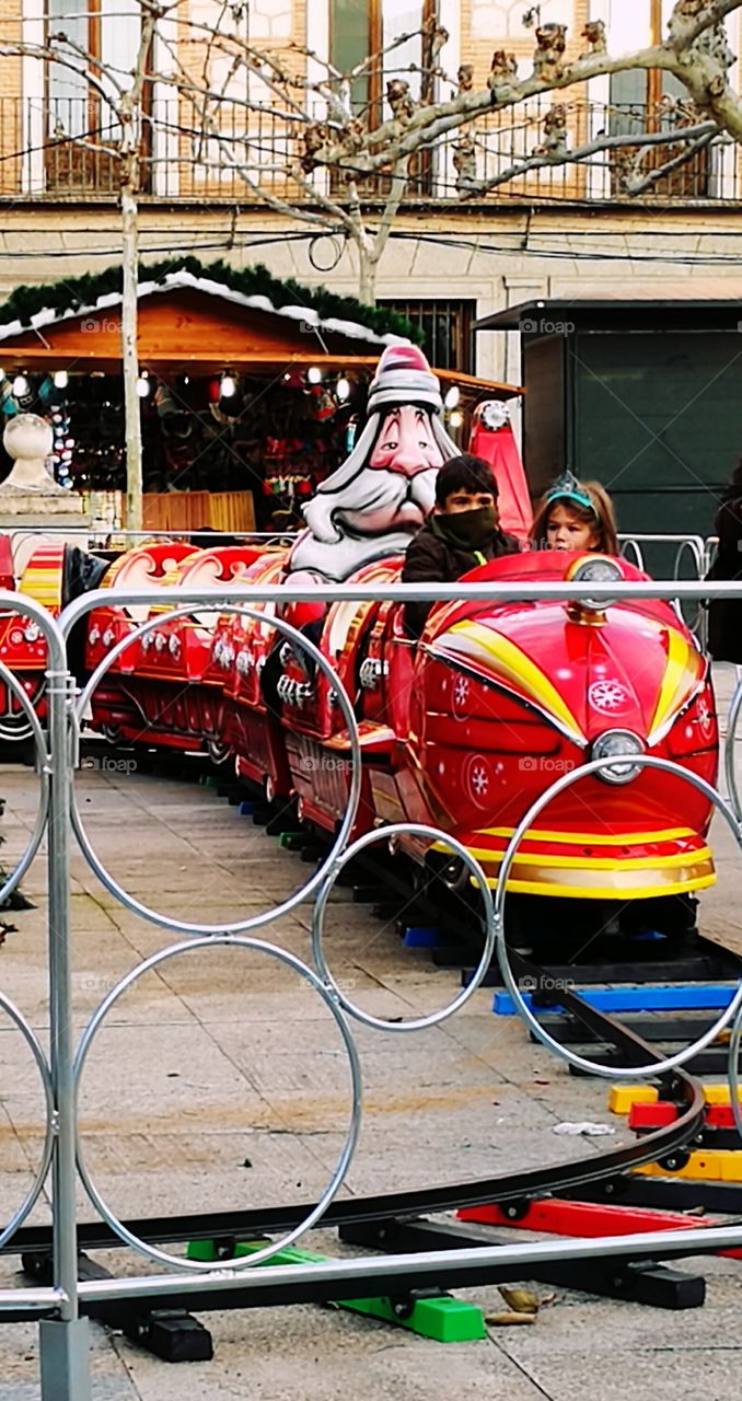 Boy and girl sitting in toy train at park