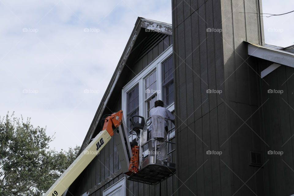 Man in a bucket cleaning windows on a house point clear Alabama