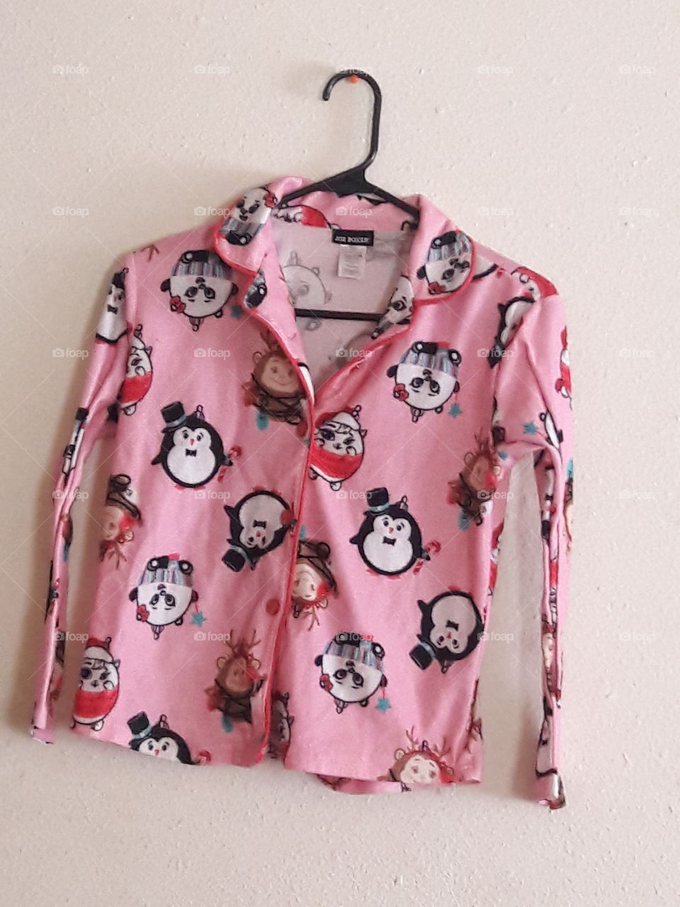 Girl's pink flannel pajama top with animal pattern hung up.