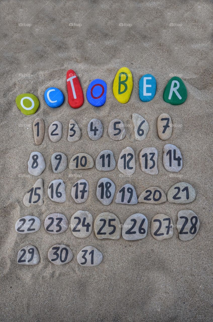 October calendar on stones with sand background