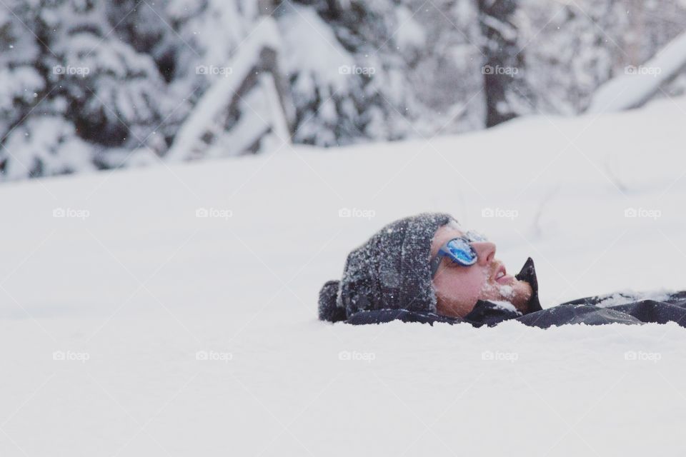 A young man lying in pure white snow