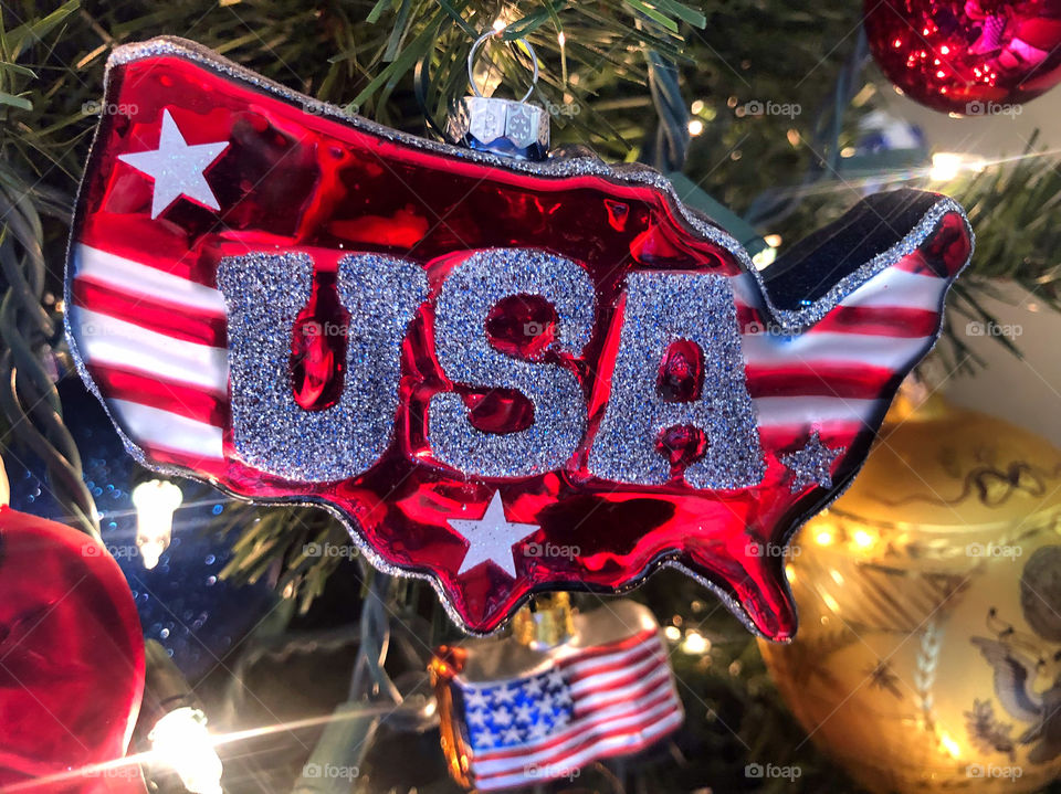 Christmas ornament in the shape of the United States of America with the word USA in silver glitter.