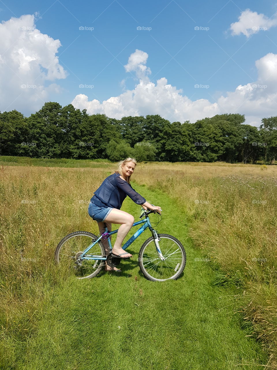 Young woman on bicycle in grassy field