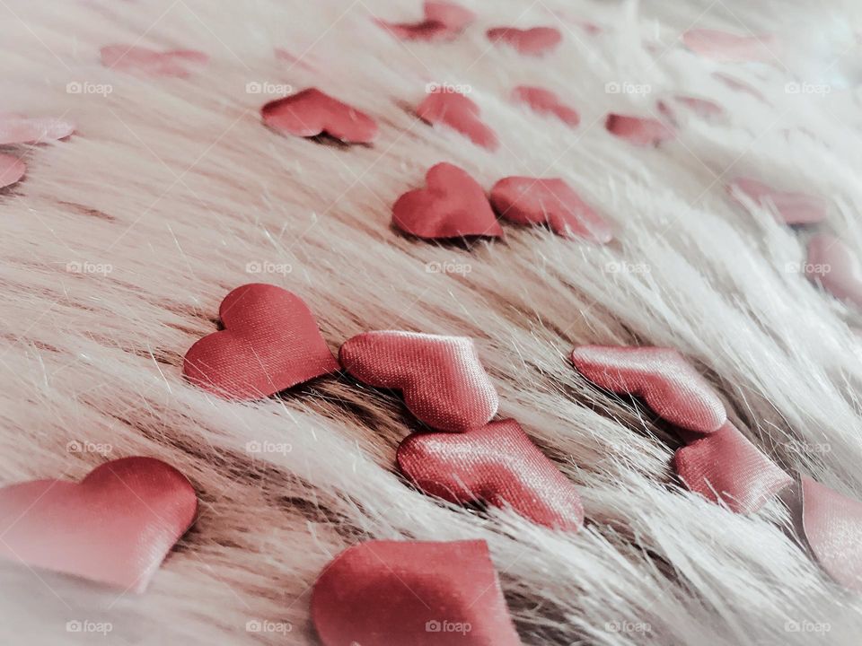 Heart shaped fabric confetti sprinkled on pink faux fur