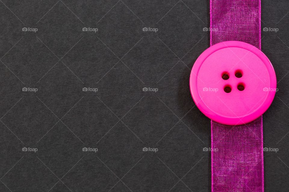 Pink button and ribbon border on black background 