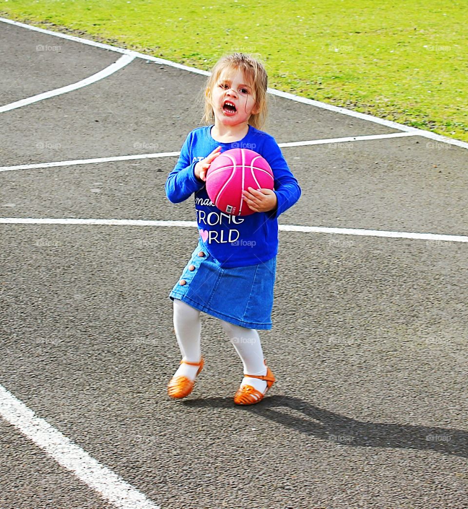 toddler girl playing basketball. she's not happy!