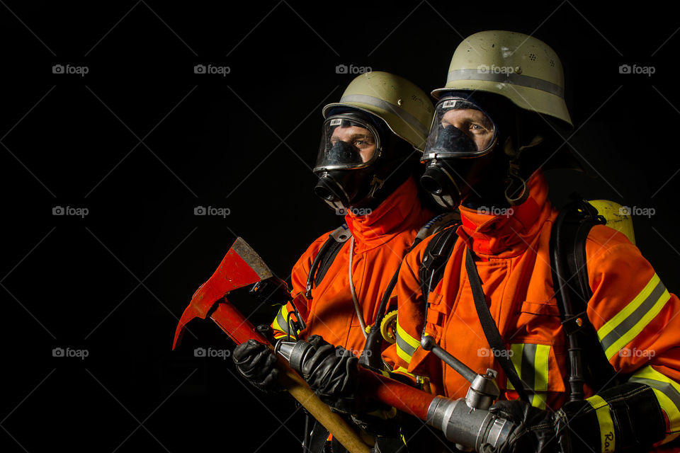 Two firefighters in black background