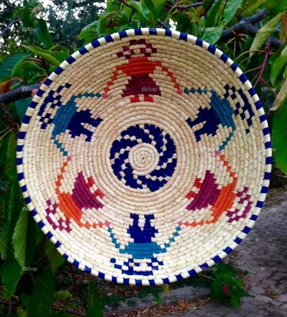 The image shows a group of hand -made dishes of wicker, decorated with colored embroideries with beautiful floral shapes, and is elegantly displayed in a warm corner that combines heritage and beauty, which gives the place an artistic spirit and attr