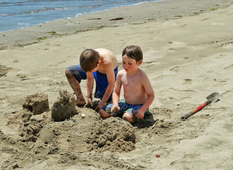 Boys On The Beach. Young Brothers Building A Sandcastle At The Beach

