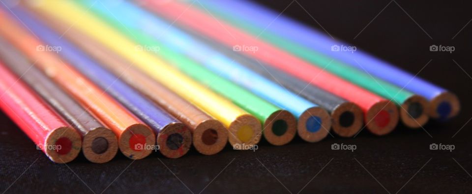 Row of colored pencil on black background
