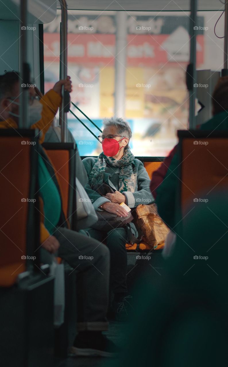 Woman with red face mask driving in tramway