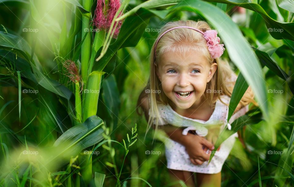 Happy little Caucasian girl with blonde hair smiling outdoor at summer day 