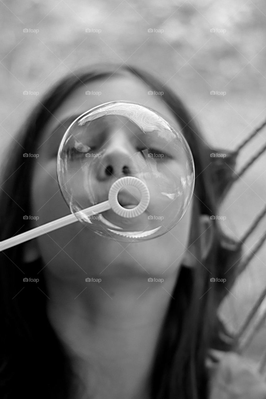 Kid blowing soap bubble b&w