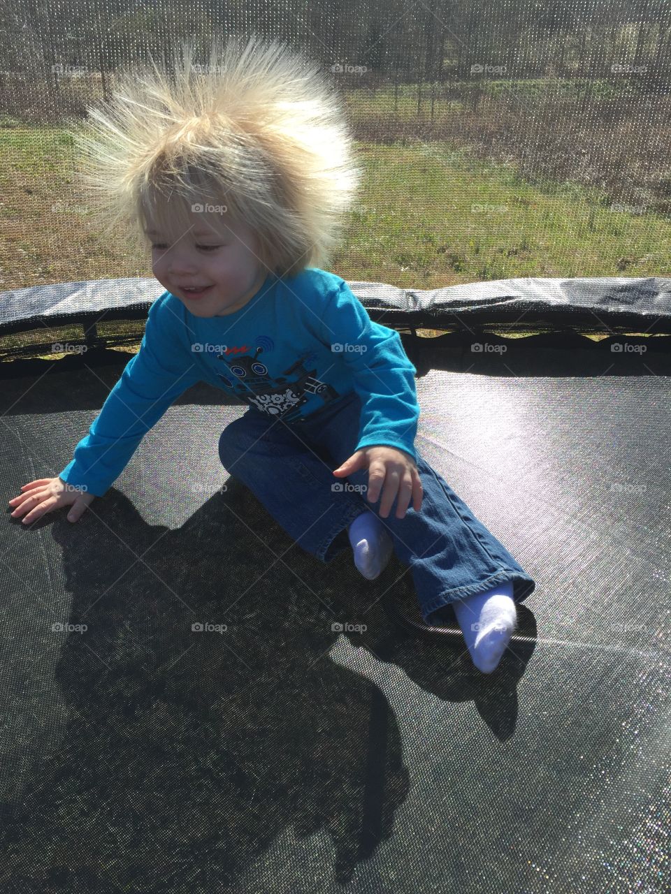 Blond boy sitting on a trampoline in the park