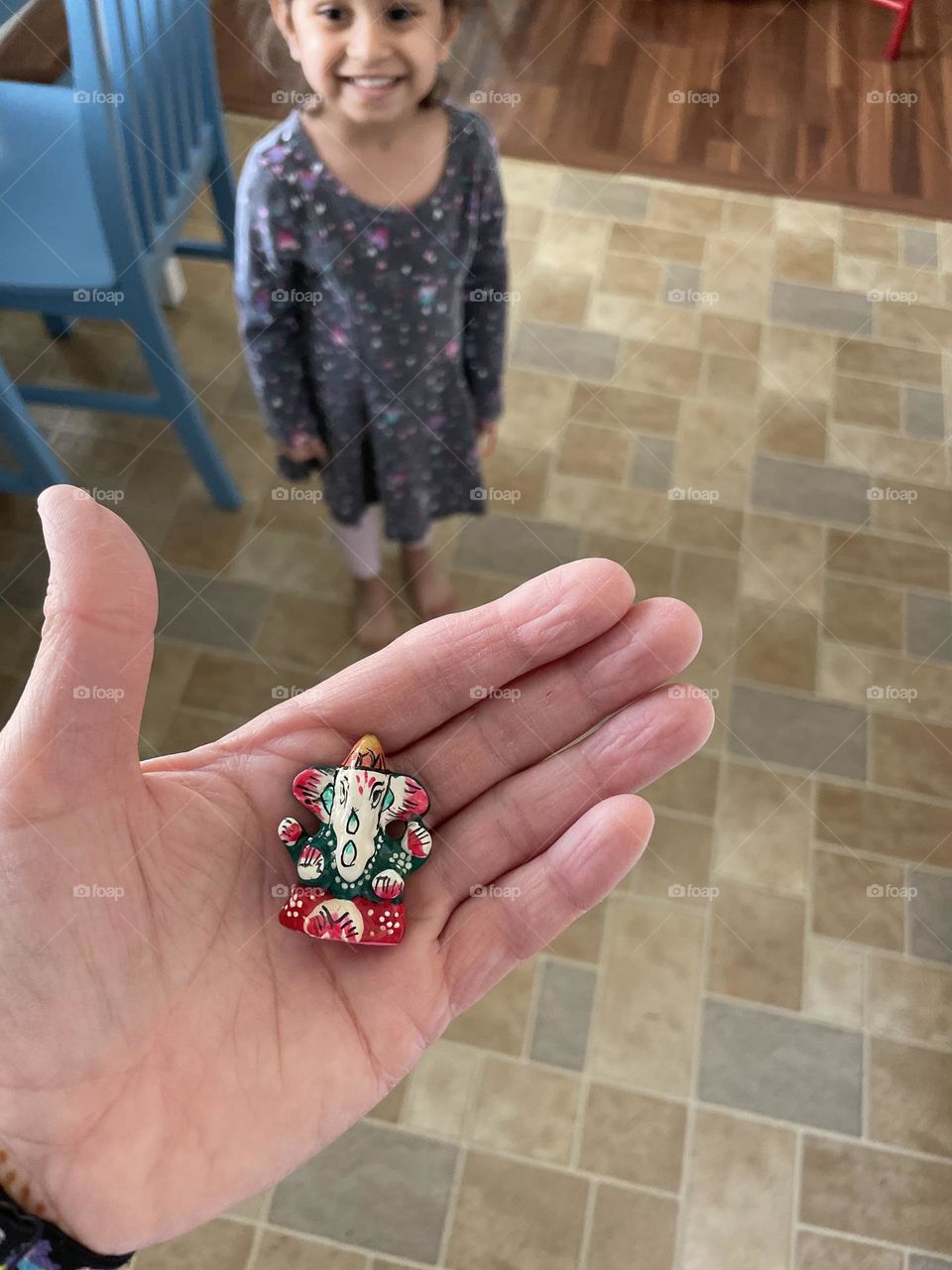 Toddler girl excited about Ganesha trinket, souvenirs from India, toddler helps Mommy unpack suitcases, small Ganesha figurine, Hindu gods from India
