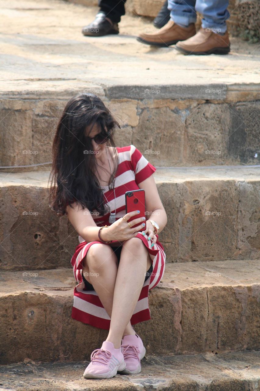 beautiful girl sitting on steps showing off her hair and taking selfie