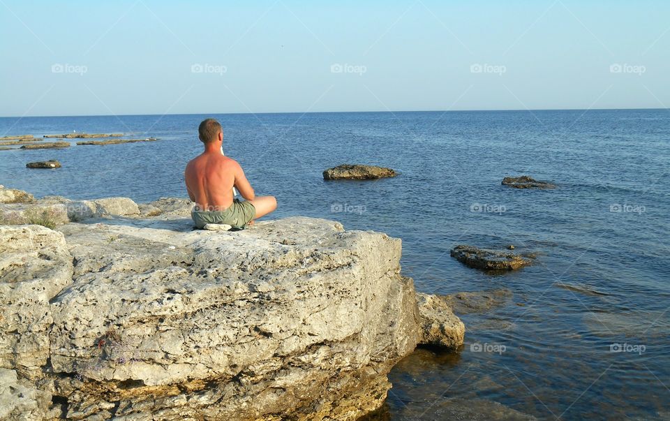 men training yoga on a sea stone shore summer time