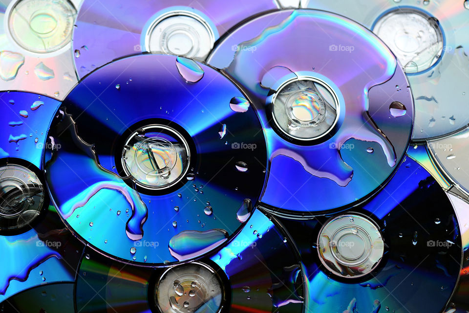 a few cd disks in blue colors covered with drop of water in a beautiful light