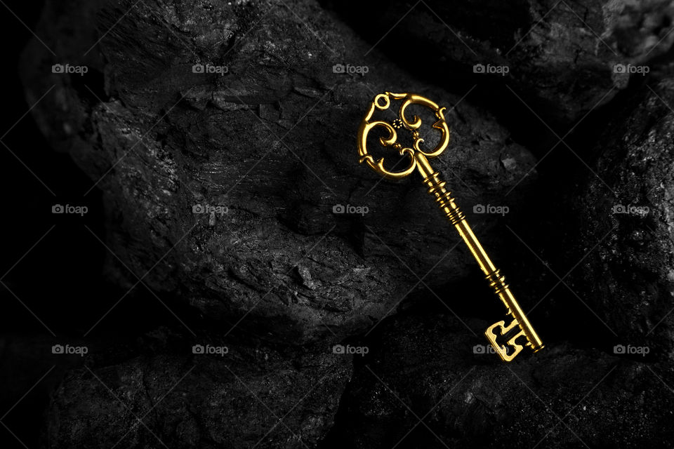 Golden antique key on black stone background