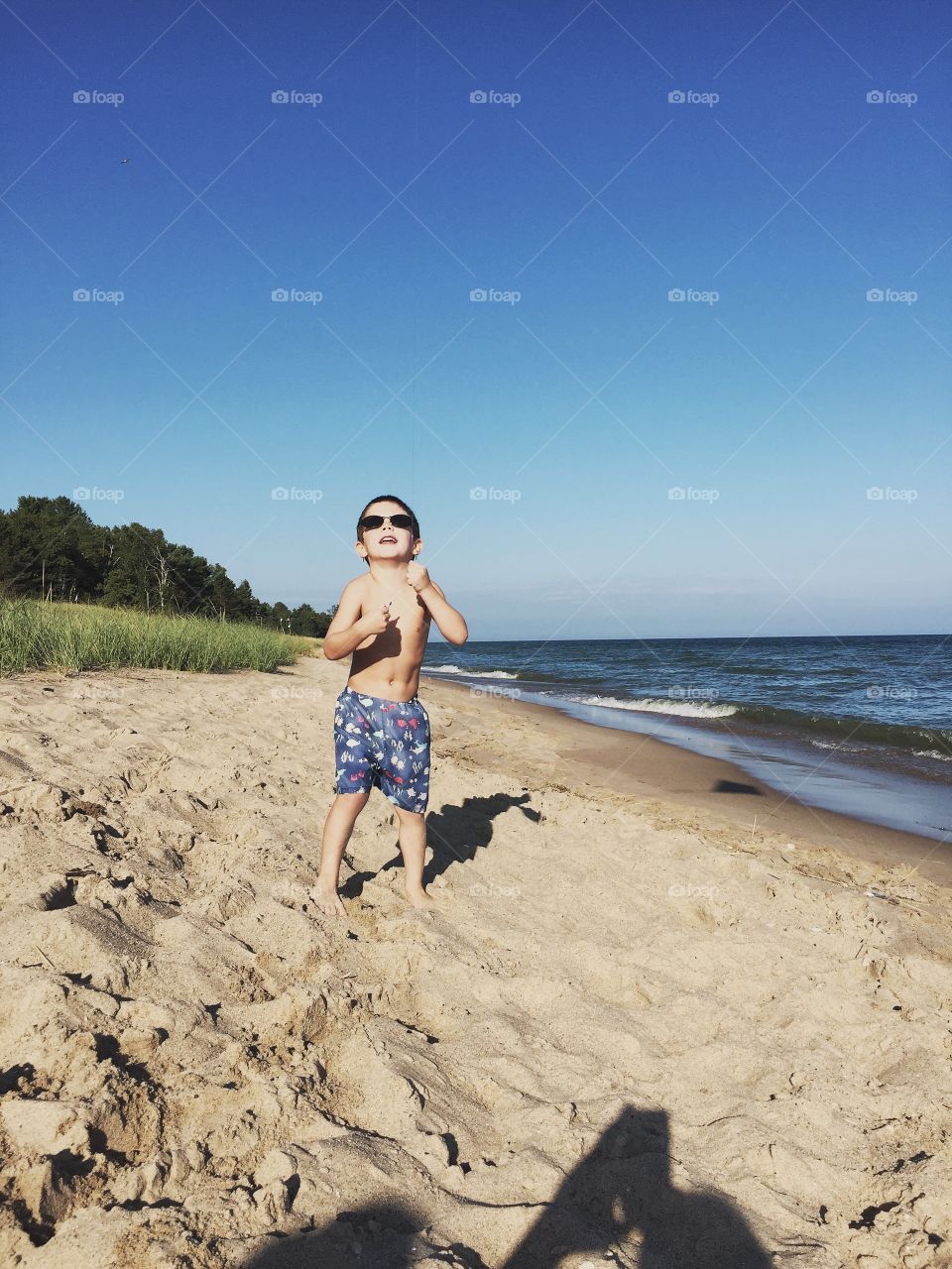 Portrait of a shirtless barefoot boy at sea shore