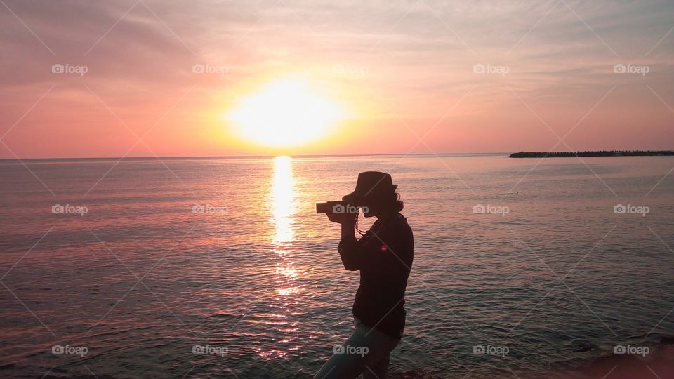 Silhouette of photographer against the sea and sunrise