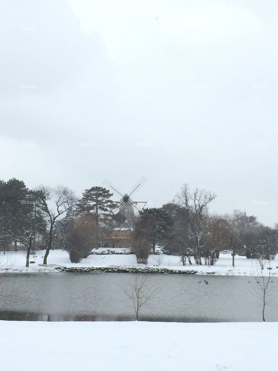 Windmill by the pond on a snowy day