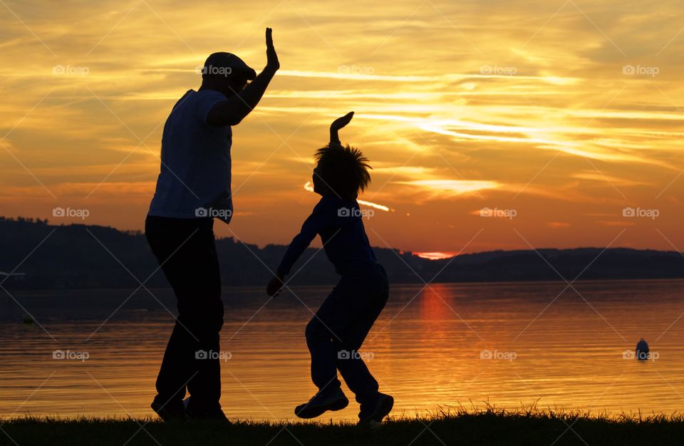 Silhouette of two people at lake