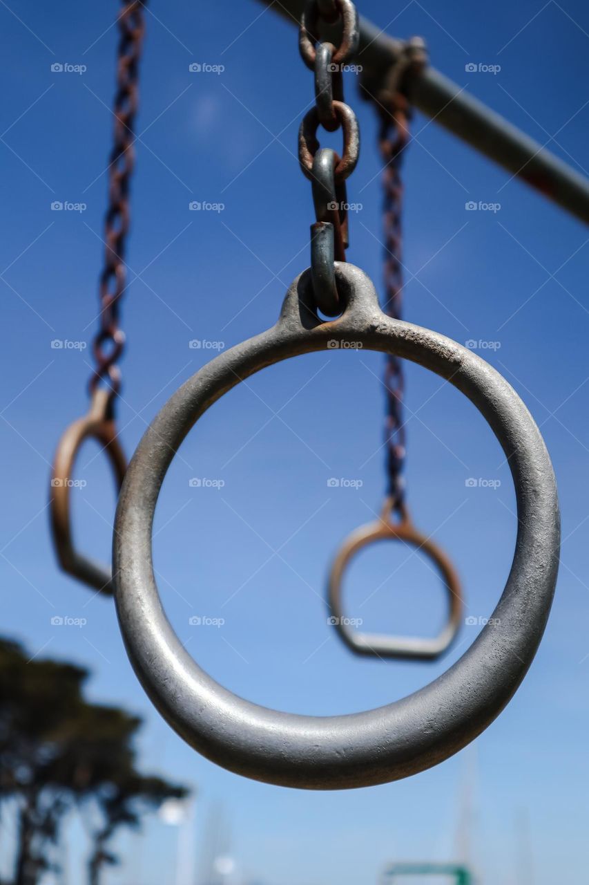 Exercise rings swinging in beautiful spring air on a warm day with blue skies, great way to use the outdoors 