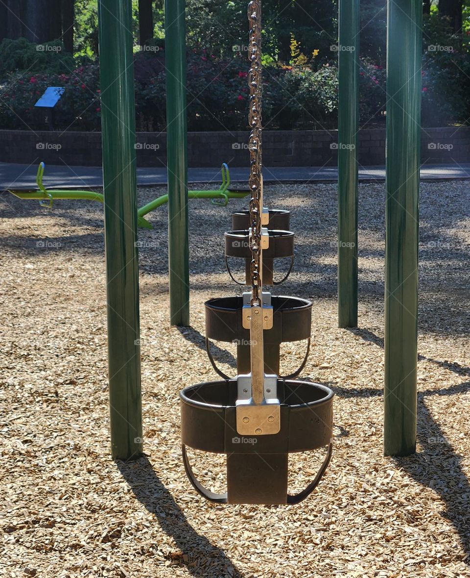 line of swings for children in an Oregon park playground on a bright Summer weekend