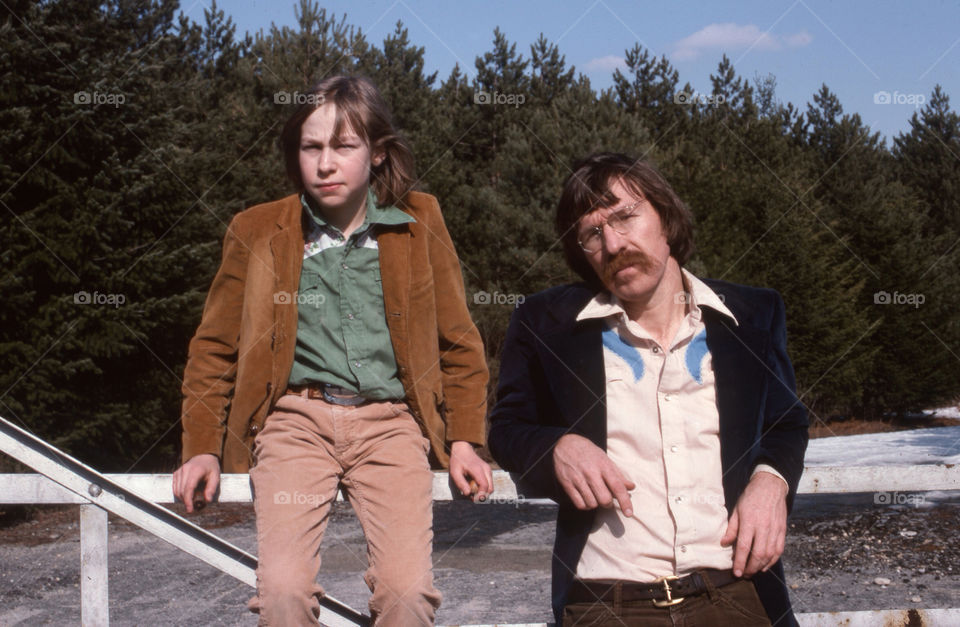 Father and son pose by a fence