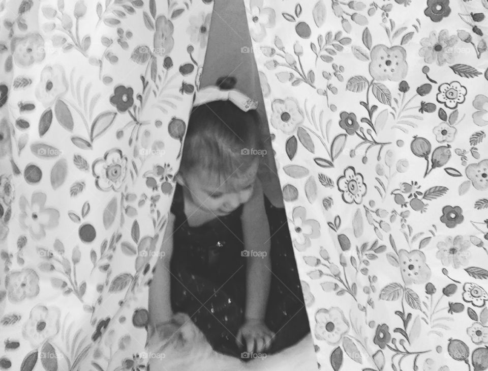 Baby girl sitting behind the curtain
