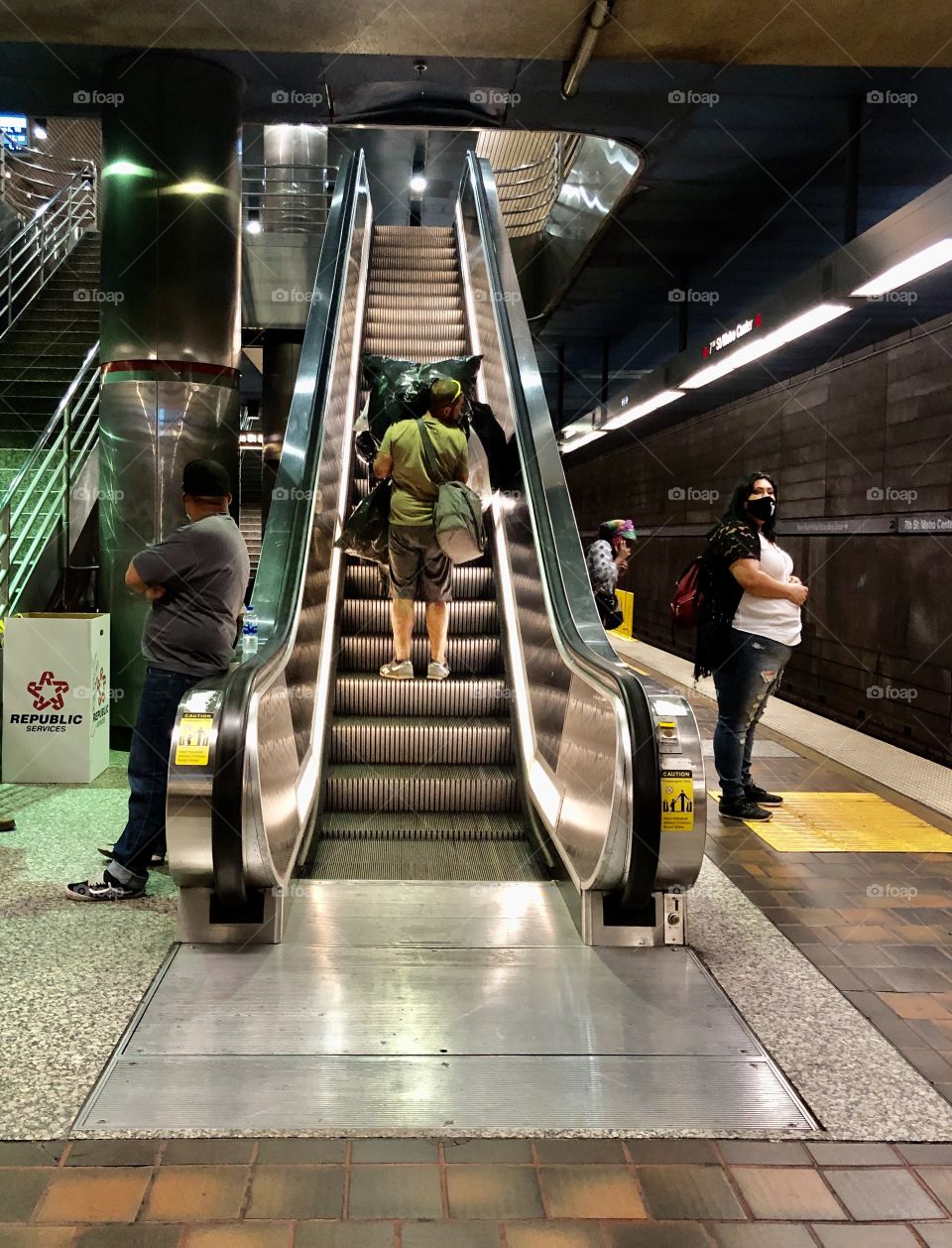 A homeless man pushes his shopping cart overloaded with belongings up an escalator at 7th St Metro Station.  Los Angeles CA 6.12.2020