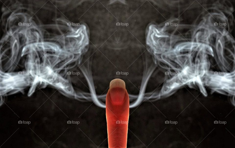 low key  close up image with smoke coming out of a finger in front of a black background