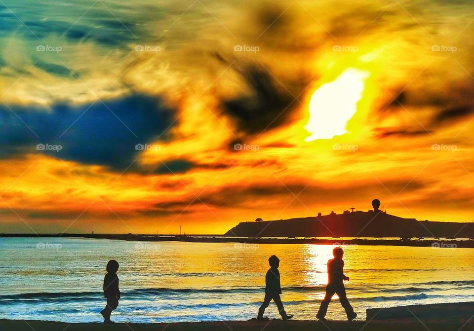 Boys near the ocean at sunset