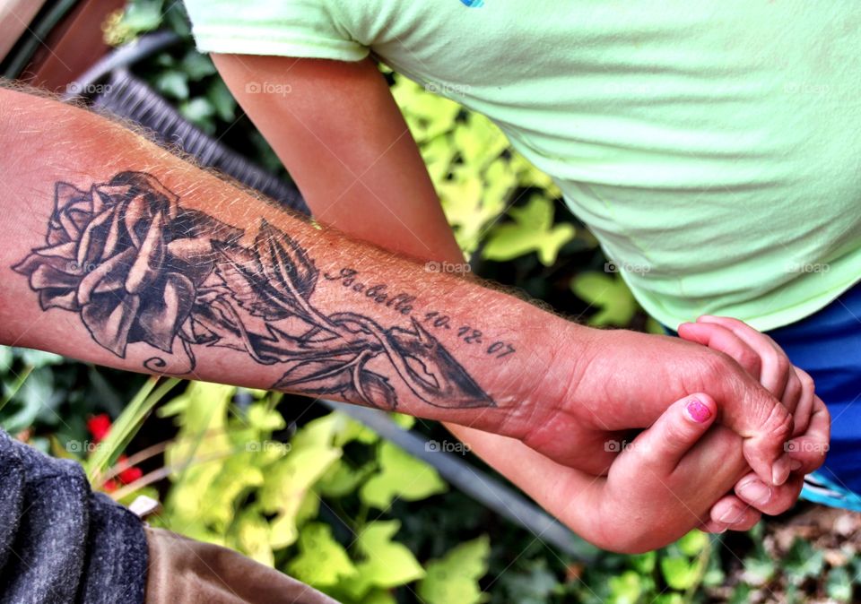 Daddy's daughter, Isabelle Rose is represented in this arm Tatoo by a rose scene with her name and date of birth! In this photo she is holding his hand at the age of 8!